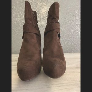 Dark brown G by Guess Graze 2 booties with gold buckles on the side.